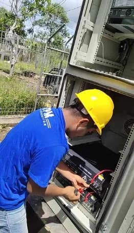 Technician dismantling battery modules at an outdoor cabinet